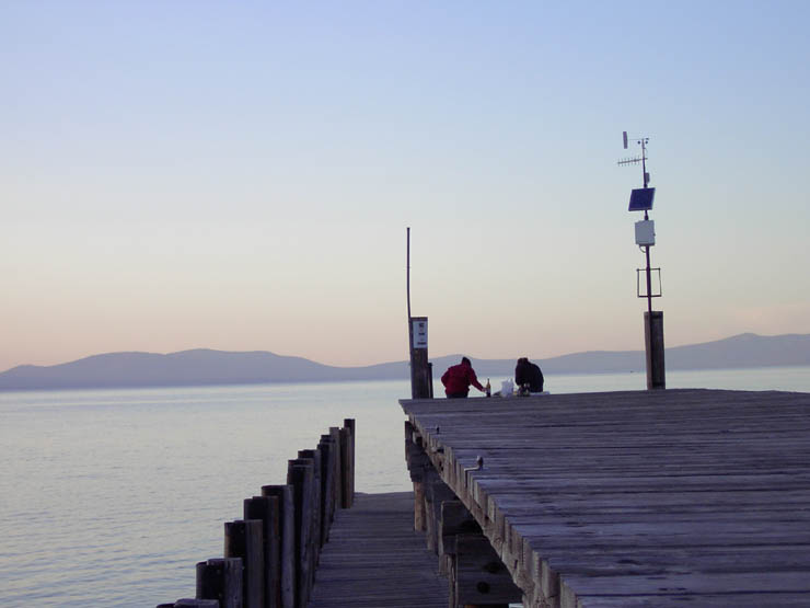 Couple eating dinner on a pier at sunset